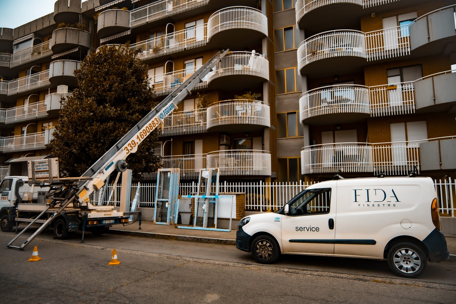 Il furgone service di Fida Finestre davanti a un condominio, con l'autoscala per i serramenti
