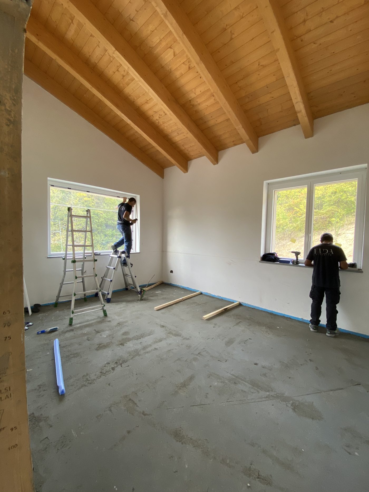 Due tecnici Fida verificano le finestre appena montate in una casa nuova con soffitto in legno